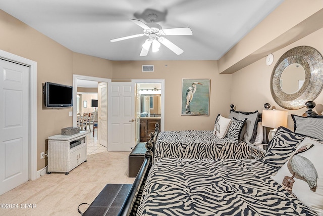 bedroom with connected bathroom, light colored carpet, and ceiling fan