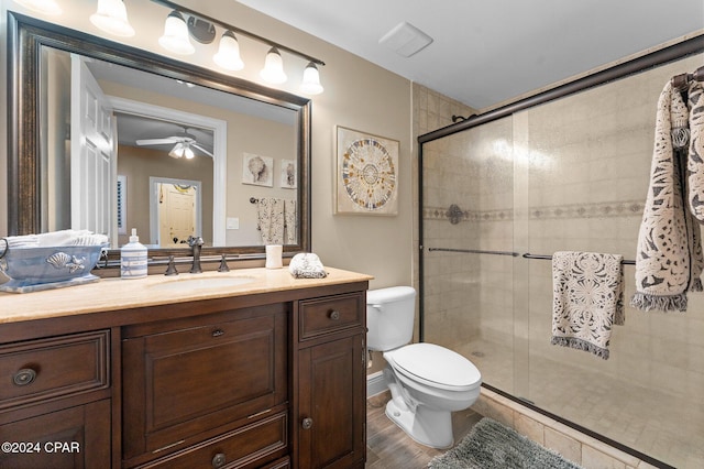 bathroom featuring walk in shower, vanity, ceiling fan, hardwood / wood-style floors, and toilet