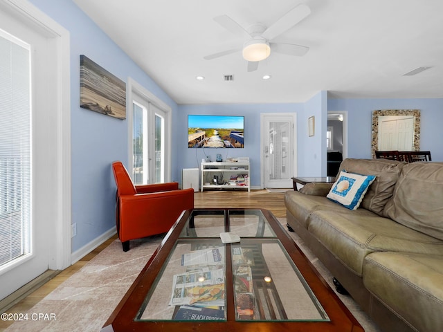 living area with visible vents, baseboards, wood finished floors, and a ceiling fan