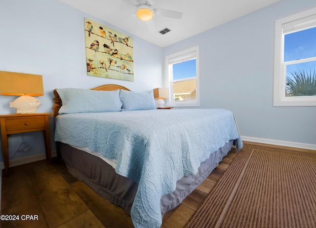 bedroom featuring ceiling fan, visible vents, baseboards, and wood finished floors