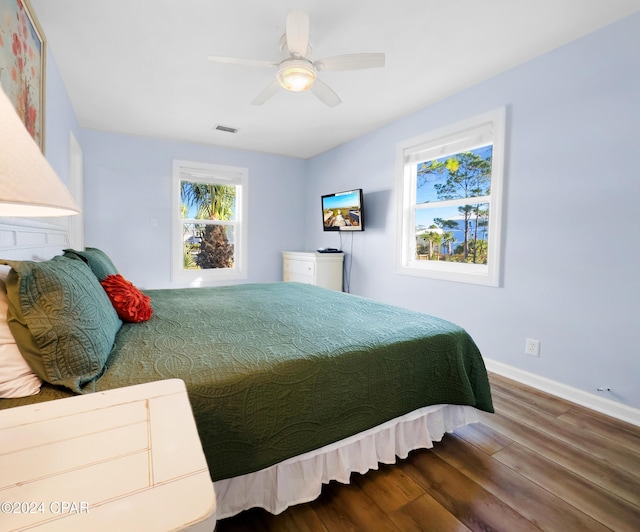 bedroom featuring ceiling fan, visible vents, baseboards, and wood finished floors