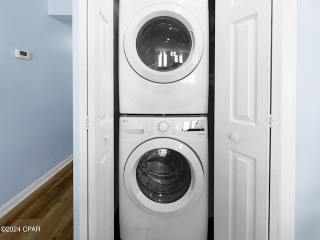 washroom with stacked washer / drying machine, baseboards, dark wood-type flooring, and laundry area