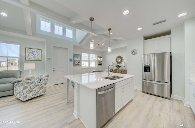 kitchen featuring sink, vaulted ceiling with beams, an island with sink, white cabinetry, and stainless steel appliances