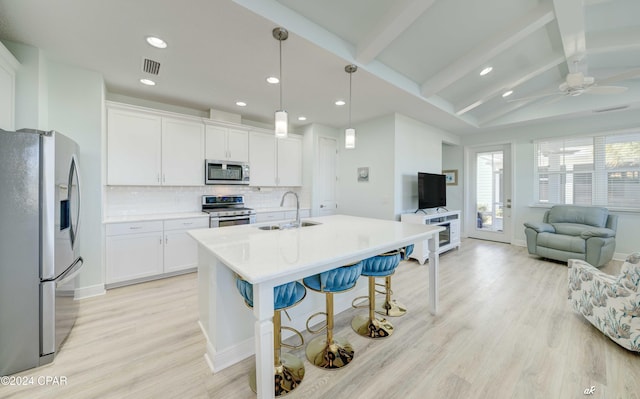 kitchen with pendant lighting, stainless steel appliances, white cabinetry, and sink