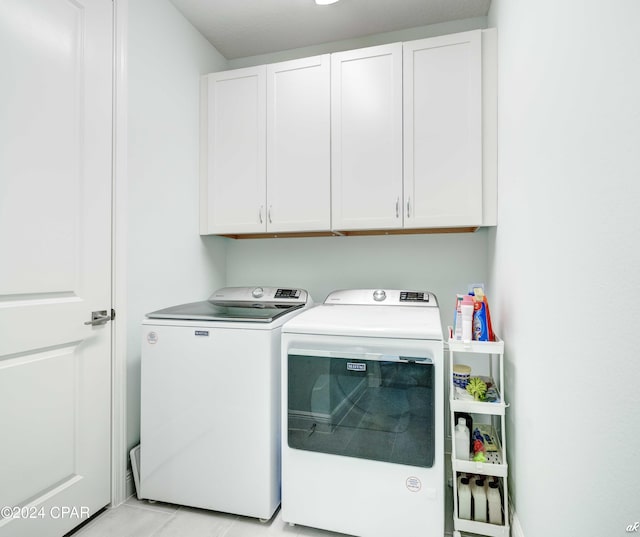 washroom with cabinets, separate washer and dryer, and light tile patterned floors