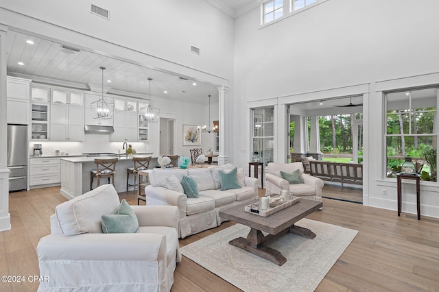 living room featuring a high ceiling, light wood-type flooring, ceiling fan, and sink