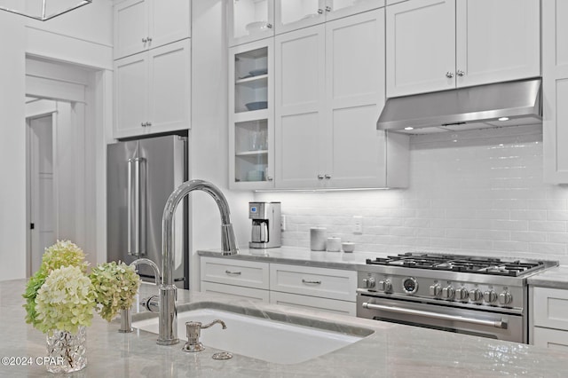 kitchen featuring high end appliances, white cabinetry, and light stone counters