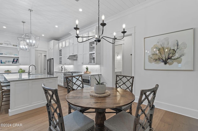 dining room with a chandelier, light wood-type flooring, ornamental molding, and sink