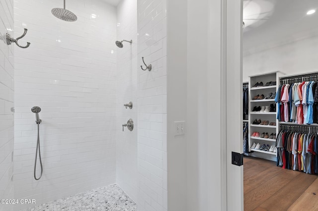 bathroom with a tile shower and wood-type flooring