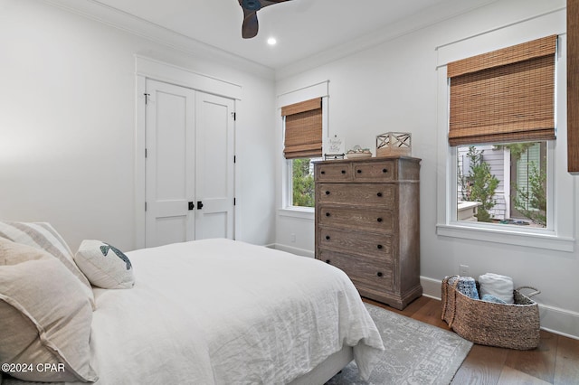 bedroom with ceiling fan, wood-type flooring, crown molding, and a closet