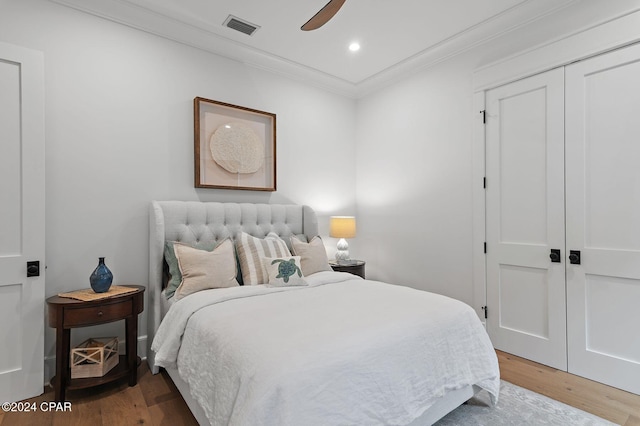 bedroom with a closet, ceiling fan, crown molding, and wood-type flooring