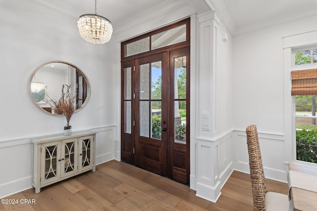 foyer entrance featuring wood-type flooring, an inviting chandelier, and crown molding