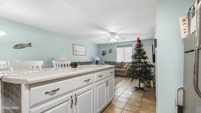 kitchen with light tile patterned floors, light countertops, a ceiling fan, and white cabinets