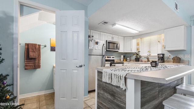 kitchen with stainless steel appliances, a breakfast bar, visible vents, and white cabinets