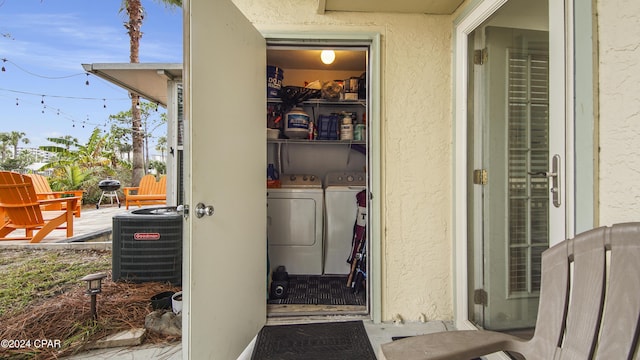 entrance to property featuring washer and dryer, cooling unit, and stucco siding