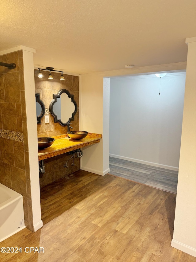 bathroom with a textured ceiling, hardwood / wood-style flooring, rail lighting, and double sink