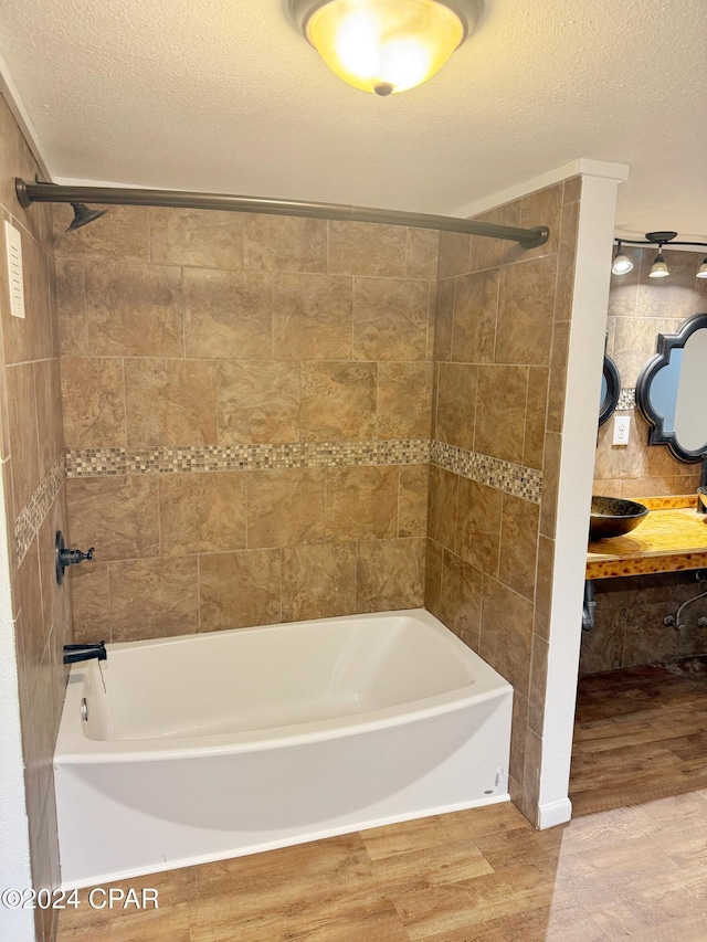 bathroom featuring hardwood / wood-style floors, a textured ceiling, and bathtub / shower combination