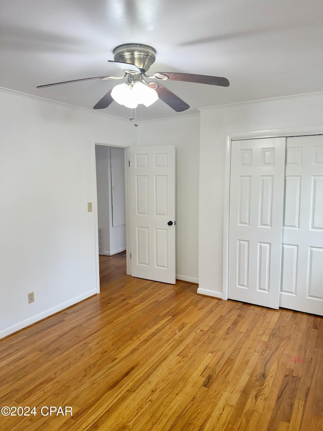 unfurnished bedroom with ceiling fan, a closet, crown molding, and light hardwood / wood-style flooring