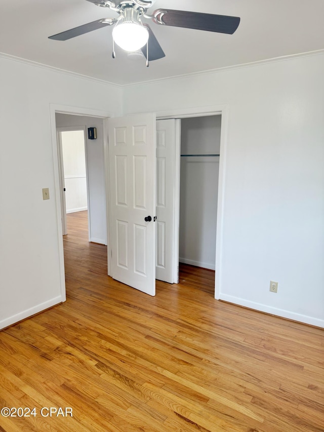 unfurnished bedroom featuring ceiling fan, a closet, ornamental molding, and light wood-type flooring