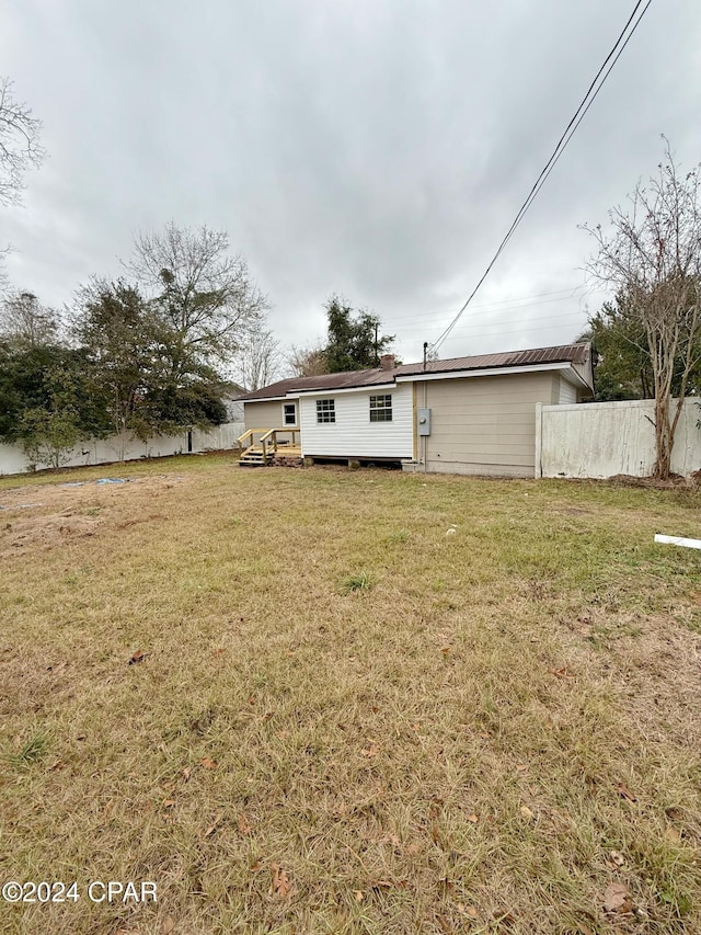 back of house featuring a wooden deck and a yard