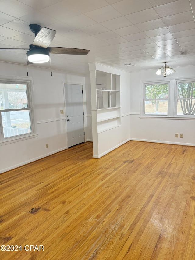 unfurnished living room featuring ceiling fan with notable chandelier and light wood-type flooring