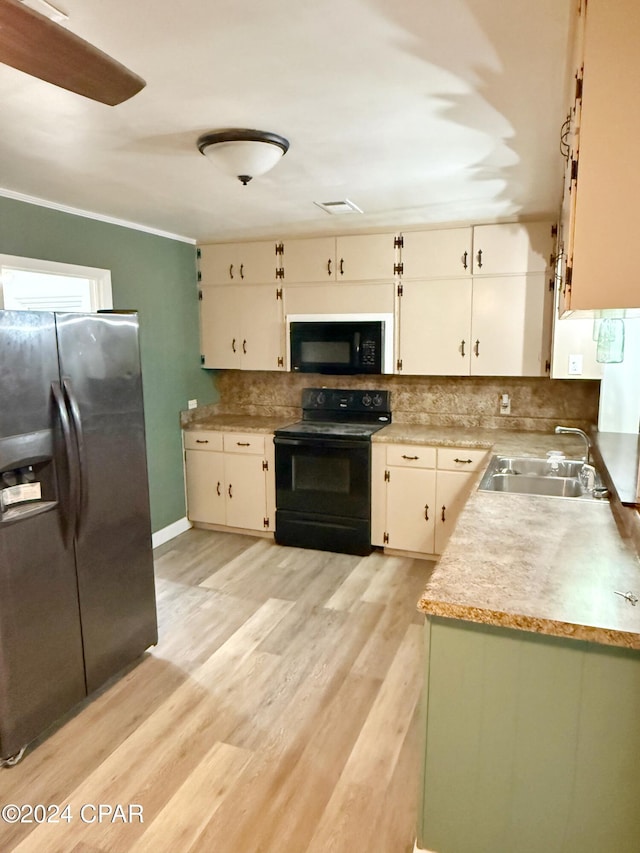 kitchen featuring light wood-type flooring, sink, white cabinetry, and black appliances