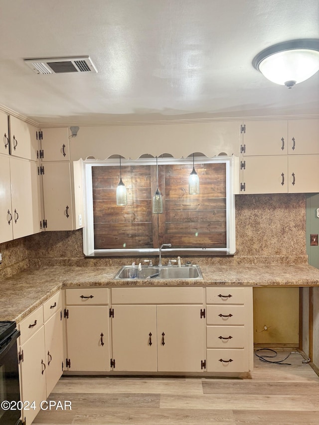 kitchen featuring light wood-type flooring, decorative light fixtures, white cabinetry, and sink