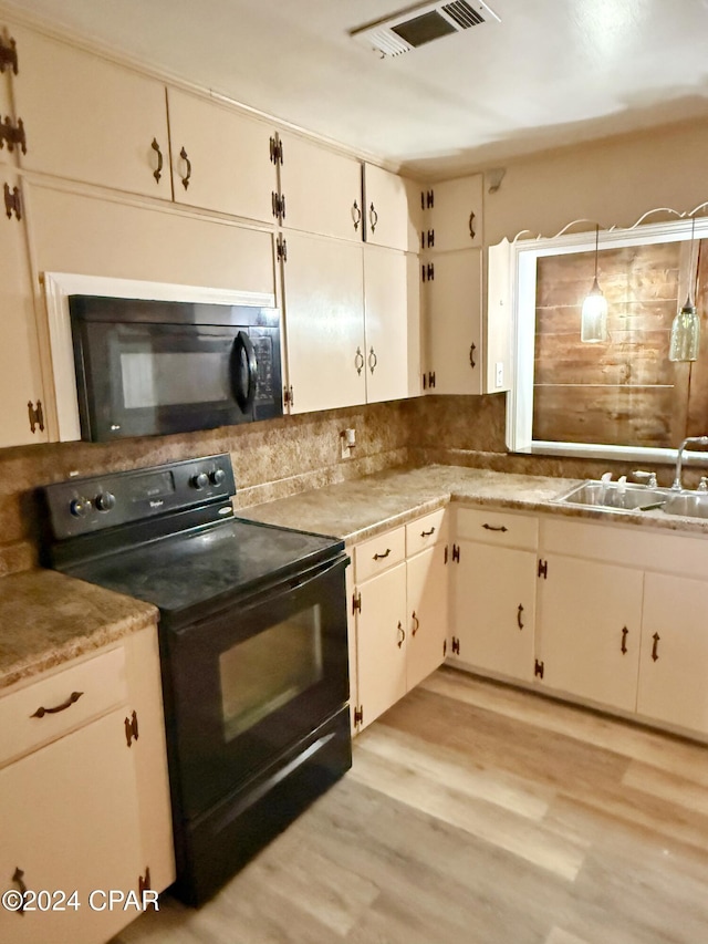 kitchen with sink, black appliances, decorative light fixtures, light hardwood / wood-style floors, and white cabinetry