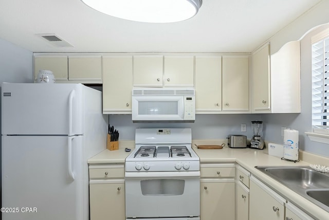 kitchen with white appliances, a sink, visible vents, light countertops, and cream cabinetry