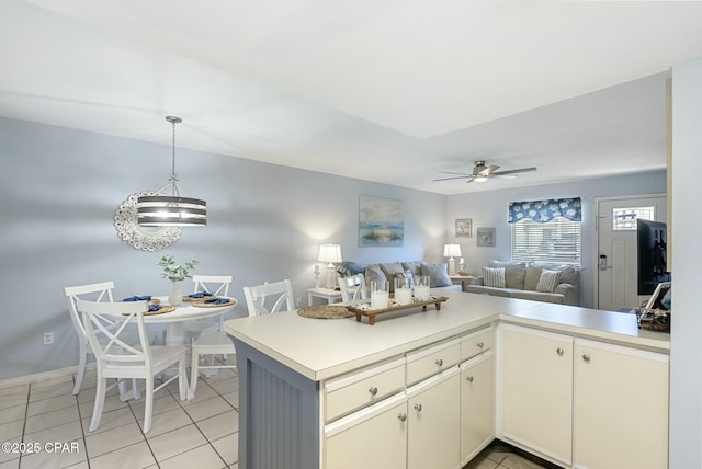 kitchen featuring light tile patterned floors, open floor plan, a peninsula, cream cabinets, and light countertops