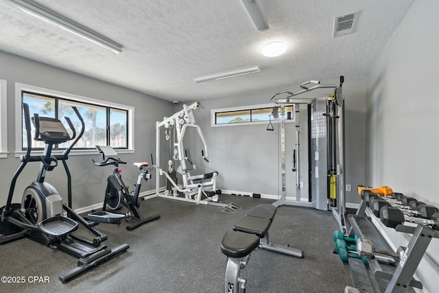 gym with visible vents, a textured ceiling, and baseboards