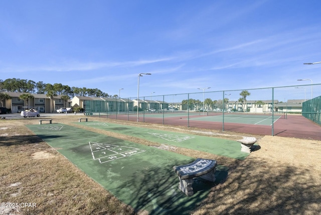 surrounding community with a residential view, a tennis court, fence, and shuffleboard