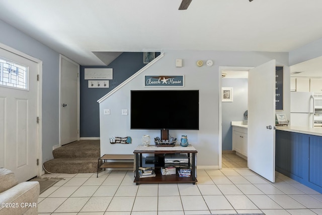 living room with light tile patterned floors, baseboards, stairway, and a ceiling fan