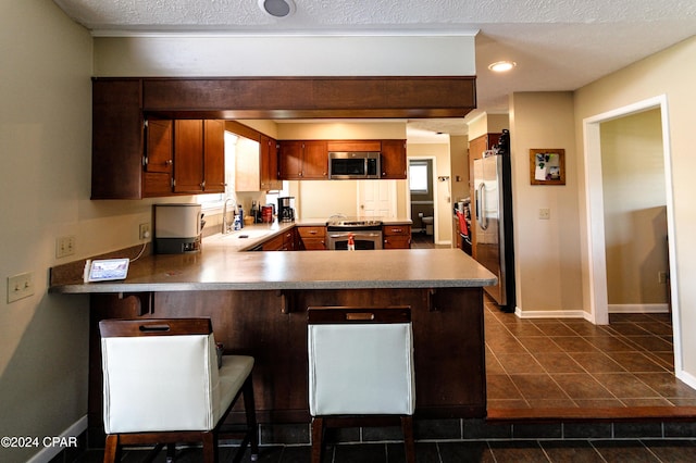 kitchen featuring kitchen peninsula, appliances with stainless steel finishes, and a breakfast bar