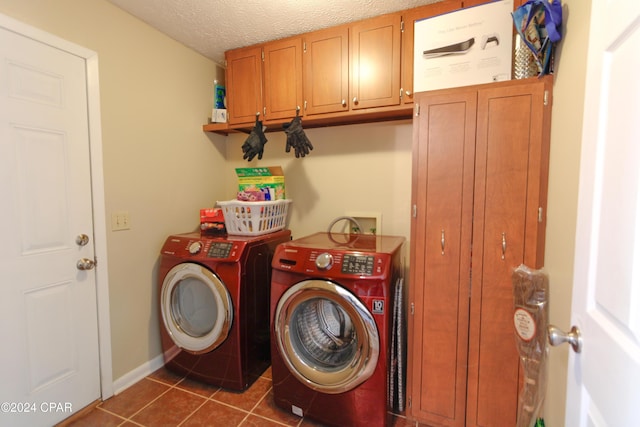 laundry area featuring a textured ceiling, cabinets, washing machine and dryer, and dark tile patterned flooring