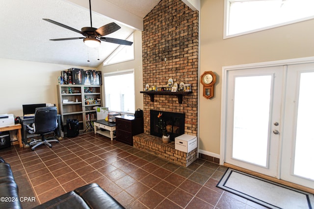 living room with a textured ceiling, vaulted ceiling, ceiling fan, a brick fireplace, and dark tile patterned floors