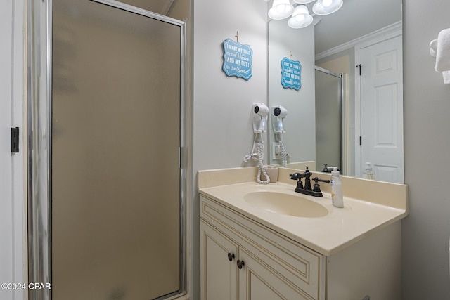 bathroom featuring vanity, a shower with shower door, and ornamental molding