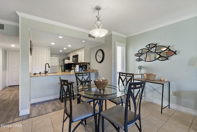 dining space featuring light tile patterned flooring, a textured ceiling, and ornamental molding