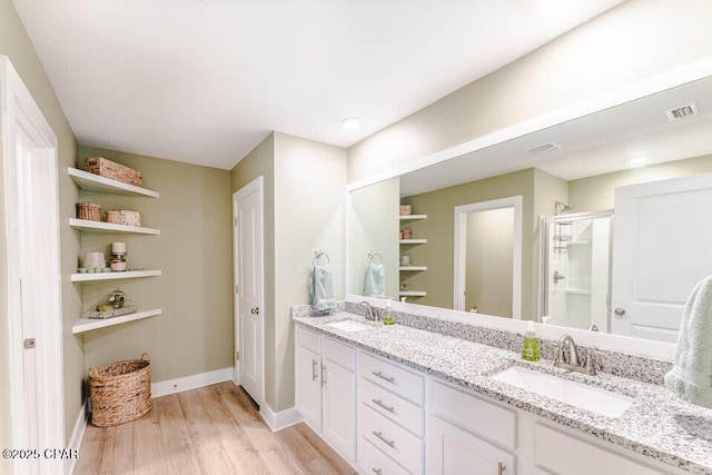 bathroom with hardwood / wood-style floors, vanity, and a shower with shower door