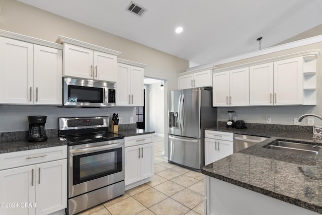 kitchen featuring white cabinetry, sink, dark stone countertops, light tile patterned floors, and appliances with stainless steel finishes