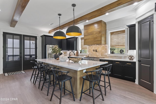 kitchen featuring stainless steel appliances, decorative backsplash, a breakfast bar, a kitchen island, and custom range hood