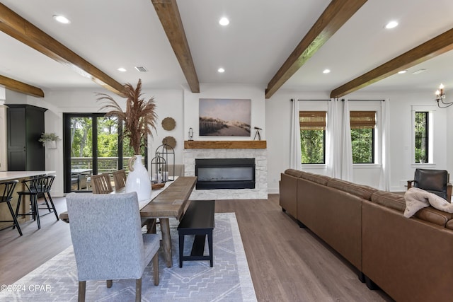 dining area with hardwood / wood-style flooring, beam ceiling, and a stone fireplace