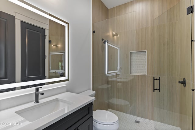 bathroom featuring a shower with door, vanity, and toilet