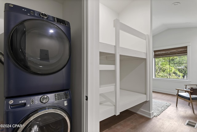 laundry area with wood-type flooring and stacked washing maching and dryer