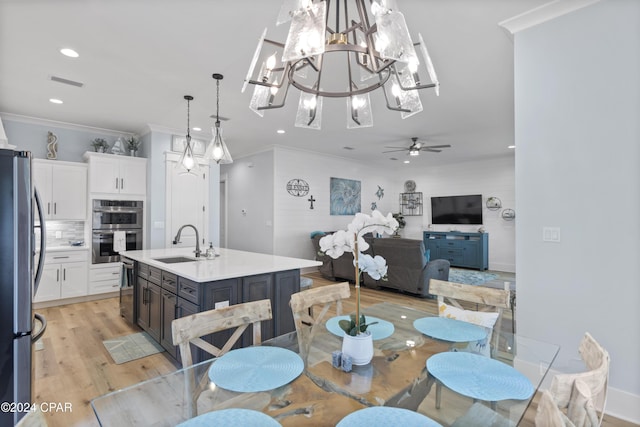 dining room with crown molding, sink, light hardwood / wood-style floors, and ceiling fan with notable chandelier