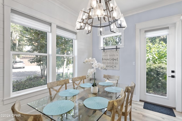 dining room featuring light hardwood / wood-style floors, crown molding, and a notable chandelier