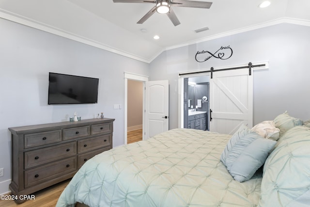 bedroom featuring ensuite bath, vaulted ceiling, ceiling fan, a barn door, and light hardwood / wood-style floors