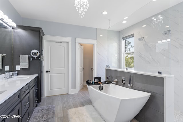 bathroom with vanity, independent shower and bath, and a notable chandelier