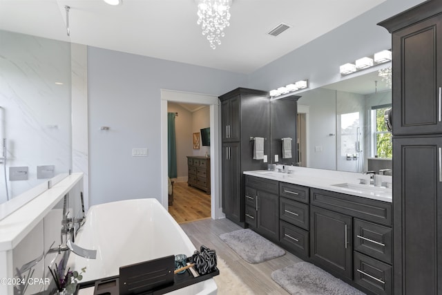 bathroom with a chandelier, vanity, and a bath