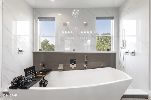 bathroom with a tub, plenty of natural light, and tile walls